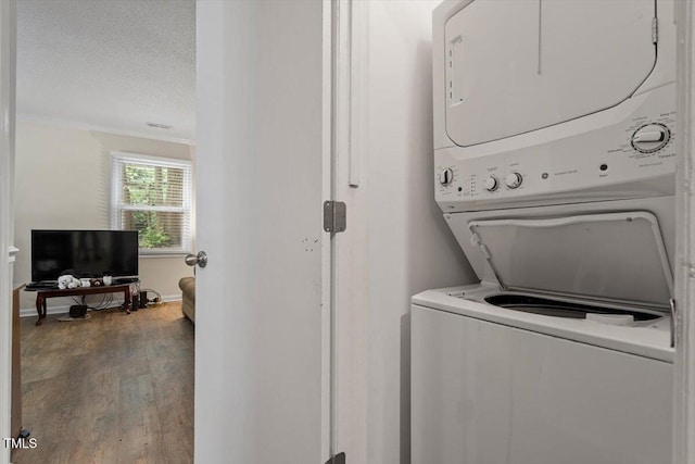washroom featuring estacked washer and dryer, wood finished floors, ornamental molding, and a textured ceiling