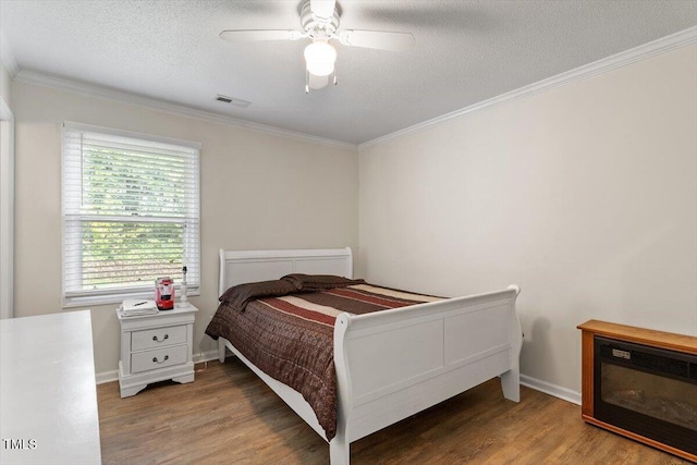 bedroom with light wood-style floors, crown molding, a textured ceiling, a ceiling fan, and baseboards
