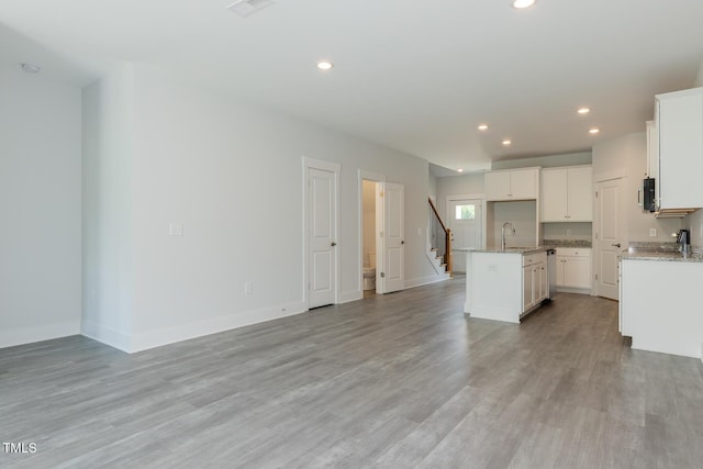 1739 Old Fields Blvd, Haw River, NC 27258 - kitchen with a center island with sink, open floor plan, recessed lighting, light stone counters, and light wood-style floors
