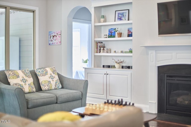 2916 Reynolda Cir, Durham, NC 27712 - living area featuring built in shelves, a fireplace with flush hearth, arched walkways, and plenty of natural light