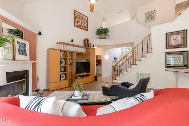 5501 Southern Cross Ave, Raleigh, NC 27606 - living area featuring a towering ceiling, baseboards, stairway, a glass covered fireplace, and tile patterned flooring