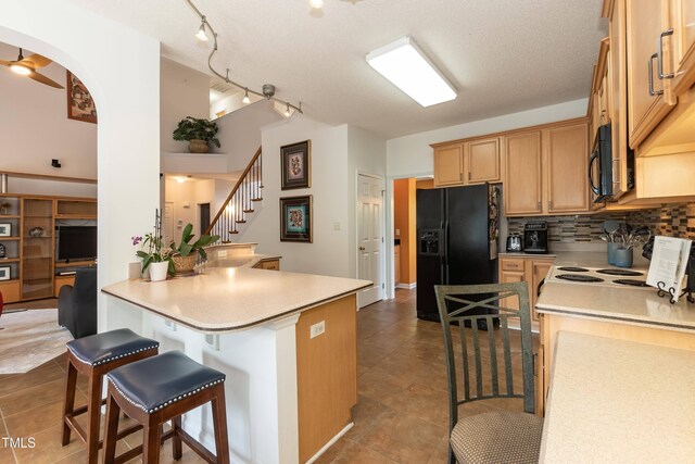5501 Southern Cross Ave, Raleigh, NC 27606 - kitchen with black appliances, a kitchen bar, tile patterned floors, tasteful backsplash, and light countertops