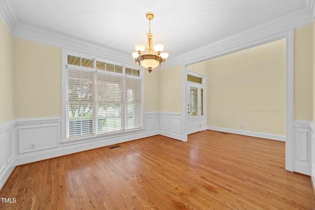 1010 Mill Pointe Way, Elon, NC 27244 - spare room with a chandelier, crown molding, wainscoting, light wood-style flooring, and a decorative wall