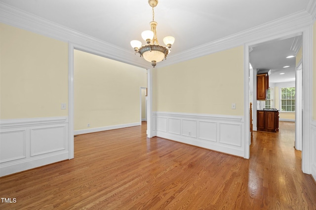 1010 Mill Pointe Way, Elon, NC 27244 - spare room featuring a chandelier, ornamental molding, wainscoting, and light wood-style floors