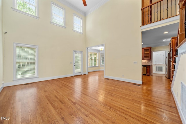 1010 Mill Pointe Way, Elon, NC 27244 - unfurnished living room featuring crown molding, light wood finished floors, a ceiling fan, a high ceiling, and baseboards