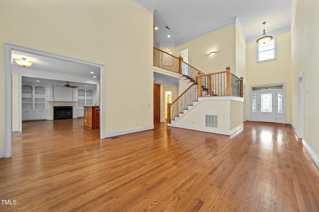 1010 Mill Pointe Way, Elon, NC 27244 - unfurnished living room with ornamental molding, a high ceiling, light wood finished floors, a fireplace, and ceiling fan