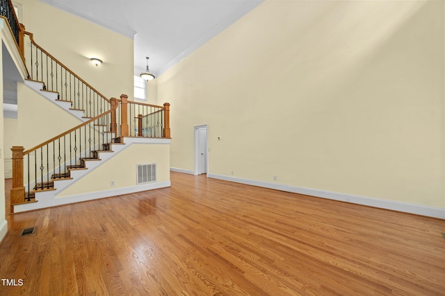 1010 Mill Pointe Way, Elon, NC 27244 - unfurnished living room featuring ornamental molding, a high ceiling, stairs, wood finished floors, and baseboards
