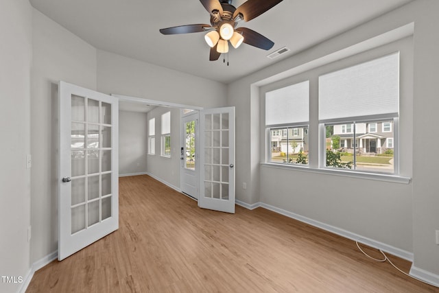 empty room with french doors, baseboards, wood finished floors, and a ceiling fan
