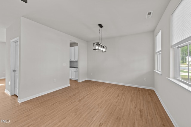 unfurnished dining area featuring light wood-type flooring and baseboards