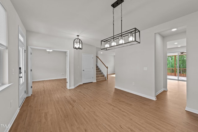 unfurnished dining area featuring light wood-type flooring, baseboards, a chandelier, stairway, and recessed lighting