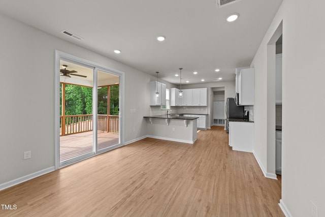 kitchen with dark countertops, white cabinetry, a breakfast bar, light wood-style flooring, and recessed lighting