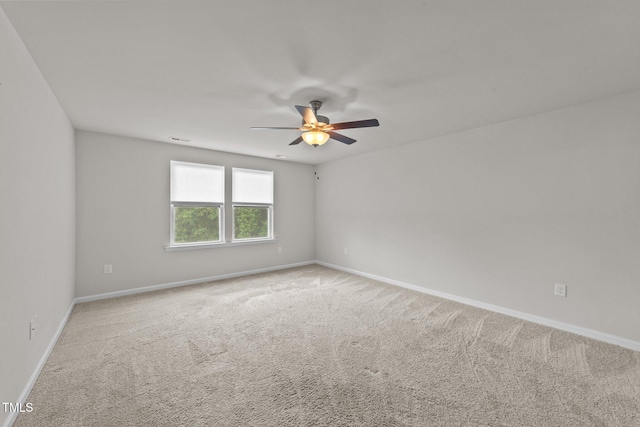 carpeted spare room with a ceiling fan and baseboards