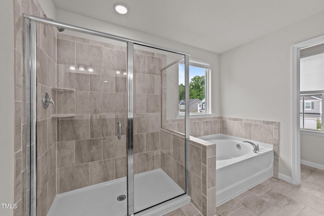 bathroom with a shower stall, a garden tub, and baseboards