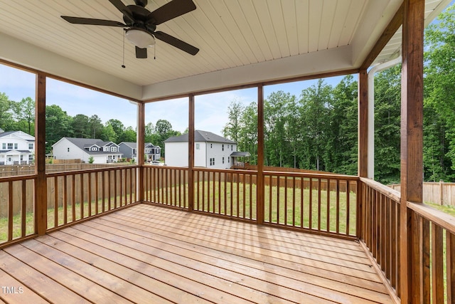 wooden deck featuring ceiling fan, a residential view, fence, and view of wooded area