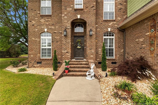 doorway to property with crawl space, brick siding, and a lawn