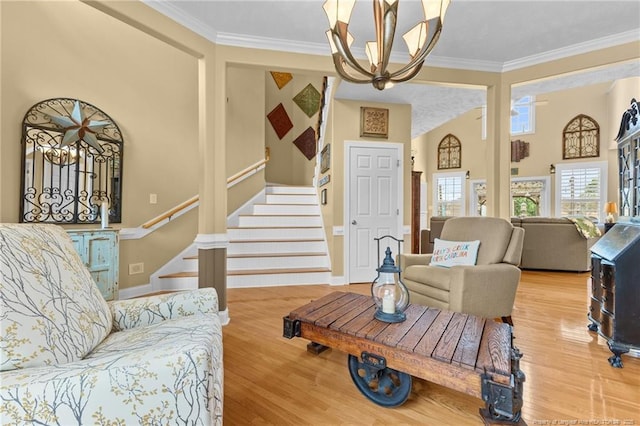 living room featuring a chandelier, stairway, ornamental molding, wood finished floors, and a high ceiling