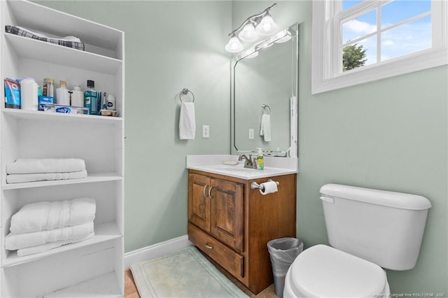 bathroom with toilet, vanity, and baseboards