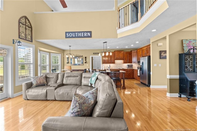 living room with a high ceiling, light wood finished floors, baseboards, and a chandelier