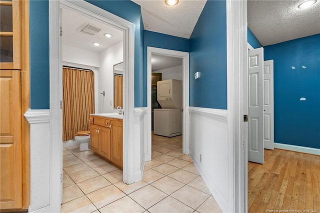 3229 Mcqueen Rd, Red Springs, NC 28377 - hallway with stacked washer / dryer, a textured ceiling, and a sink