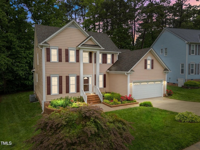 greek revival inspired property featuring concrete driveway, central air condition unit, roof with shingles, and a front lawn