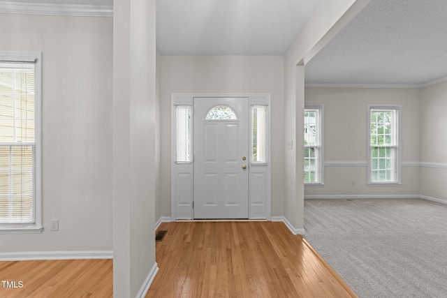 foyer entrance featuring light wood-style floors, baseboards, and ornamental molding