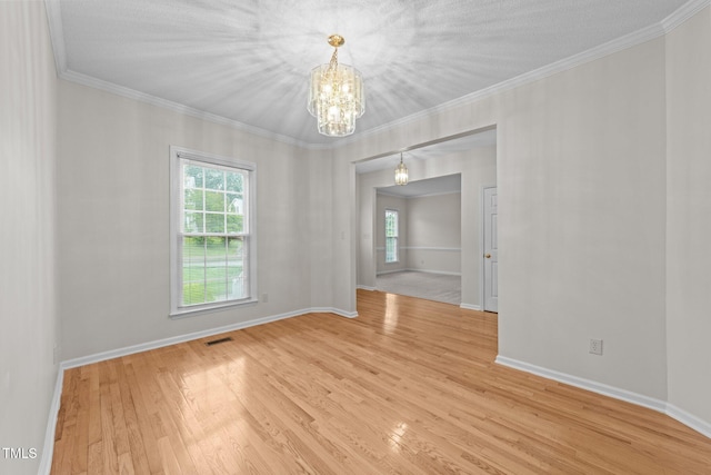 spare room with a chandelier, wood finished floors, baseboards, and ornamental molding