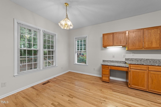 kitchen with a chandelier, light wood-style flooring, plenty of natural light, and pendant lighting