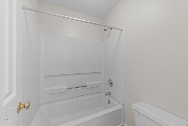 bathroom with a textured ceiling, toilet, and washtub / shower combination