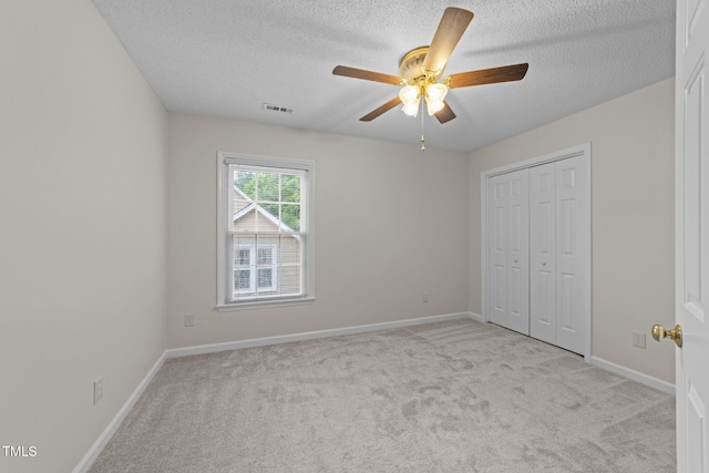 unfurnished bedroom featuring a textured ceiling, light carpet, a closet, and baseboards