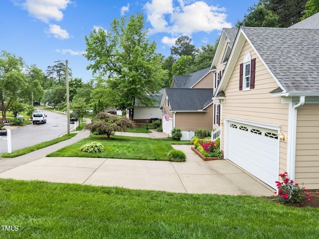 view of front of house with roof with shingles, an attached garage, concrete driveway, and a front lawn