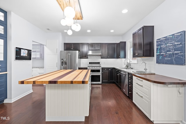 kitchen featuring premium appliances, butcher block countertops, a sink, dark wood-style flooring, and recessed lighting