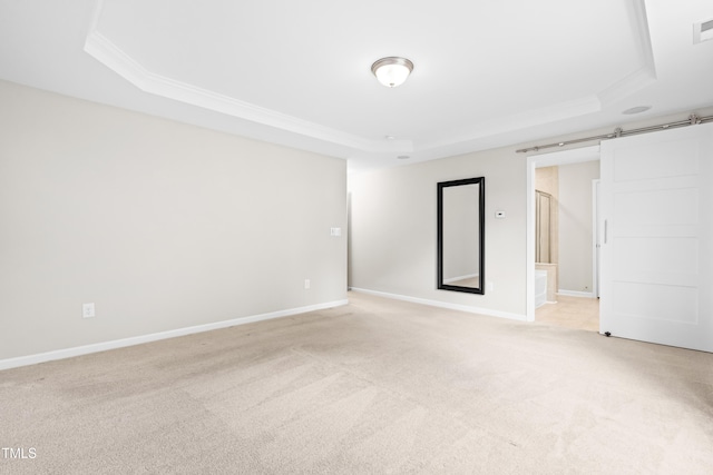 unfurnished room with a raised ceiling, crown molding, light colored carpet, and baseboards