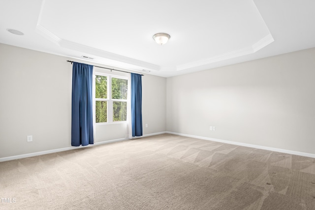 carpeted spare room featuring a tray ceiling, baseboards, and crown molding