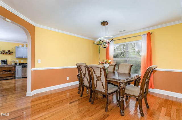 412 Collington Dr, Mebane, NC 27302 - dining room featuring arched walkways, baseboards, light wood-style floors, and crown molding