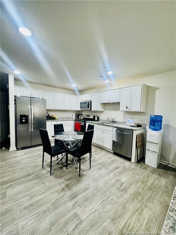 3202 Finch Ct, Sanford, NC 27332 - kitchen featuring appliances with stainless steel finishes, a sink, light wood finished floors, and white cabinetry