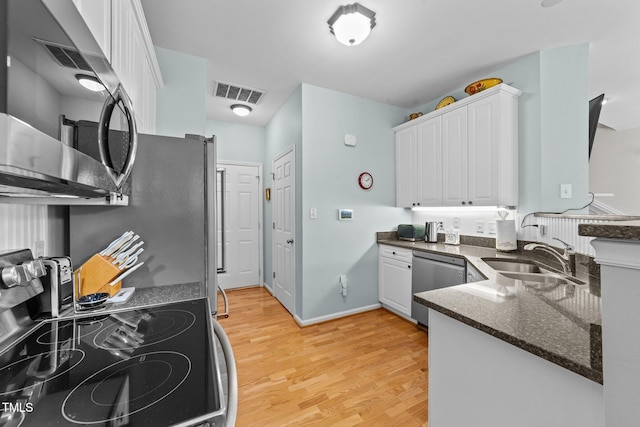 11013 Louson Pl, Raleigh, NC 27614 - kitchen with a sink, appliances with stainless steel finishes, white cabinets, light wood-type flooring, and dark stone counters