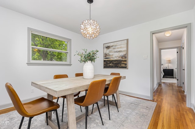 dining room featuring light wood-style flooring, baseboards, and a chandelier
