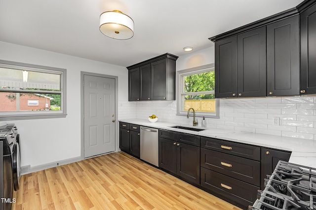 kitchen with a sink, washing machine and dryer, dishwasher, light wood-style flooring, and decorative backsplash