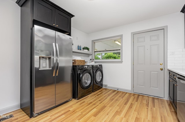 kitchen featuring stainless steel appliances, washer and dryer, light wood finished floors, tasteful backsplash, and light countertops