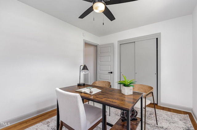 dining room featuring a ceiling fan, baseboards, wood finished floors, and an office area