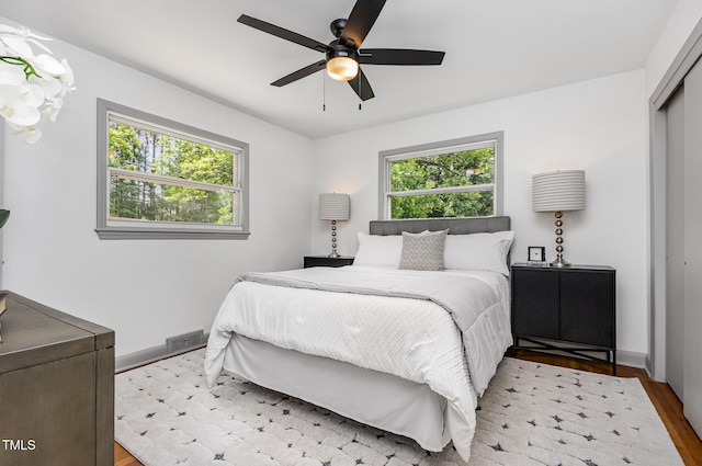 bedroom featuring wood finished floors, a closet, ceiling fan, and baseboards