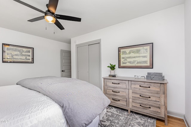 bedroom featuring a closet, light wood finished floors, a ceiling fan, and baseboards