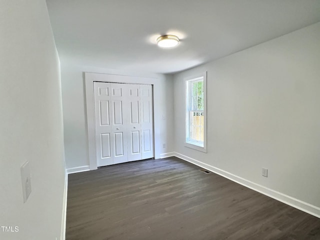114 N Guthrie Ave, Durham, NC 27703 - unfurnished bedroom featuring baseboards, dark wood-style flooring, and a closet
