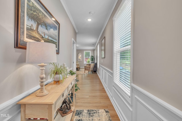 hall with crown molding, light wood finished floors, wainscoting, a decorative wall, and recessed lighting