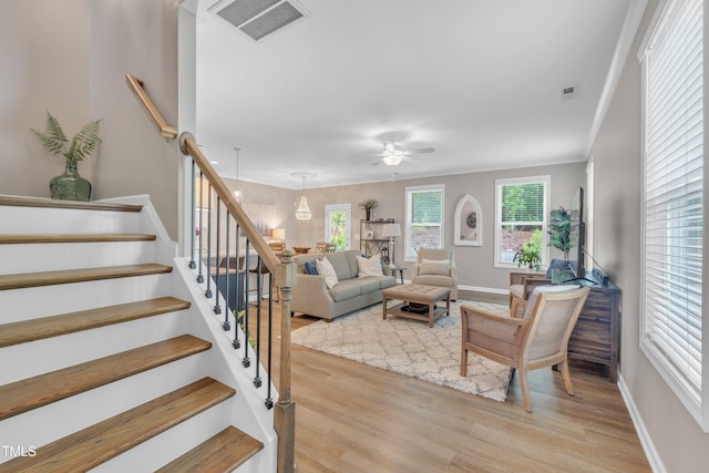living area with a ceiling fan, light wood-type flooring, stairs, and baseboards