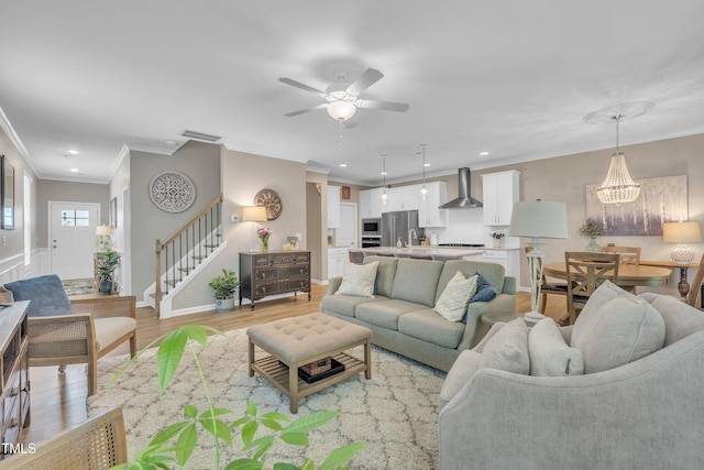 living room featuring stairway, ceiling fan, ornamental molding, light wood-type flooring, and baseboards