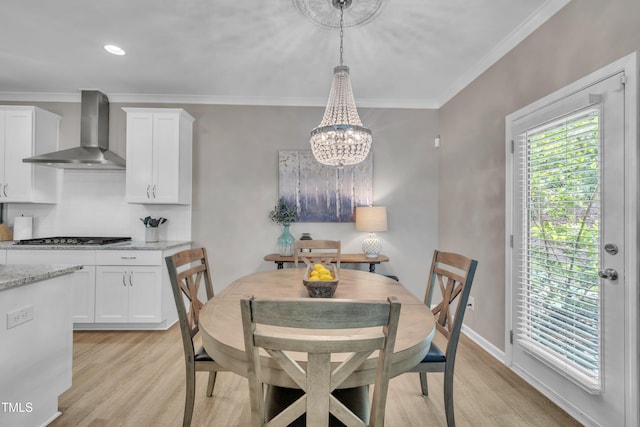 dining space featuring light wood-style floors, crown molding, a chandelier, and baseboards
