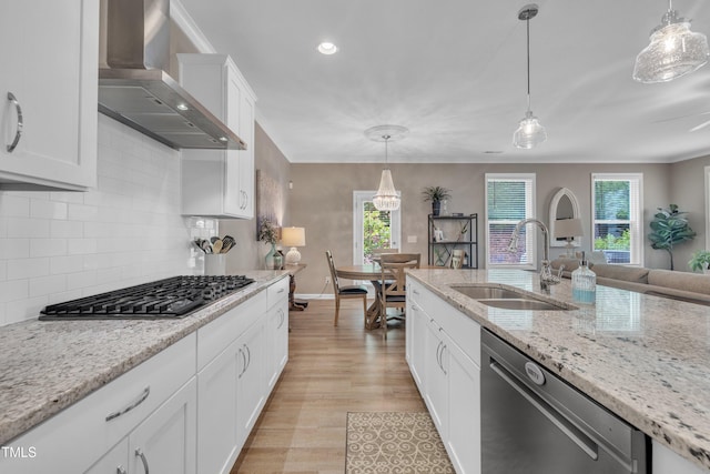 kitchen featuring wall chimney exhaust hood, a sink, stainless steel appliances, light wood-style flooring, and crown molding
