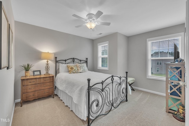 bedroom with light colored carpet, multiple windows, baseboards, and a ceiling fan