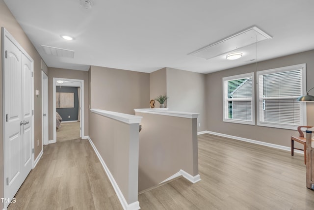 corridor with attic access, an upstairs landing, light wood-style flooring, and baseboards